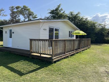A chalet with a deck and umbrella at Chalet 3 Wipeout in Hayle