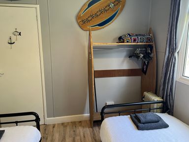 A bedroom with two beds and a surfboard on the wall at Chalet 3 Wipeout in Hayle