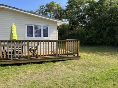 An outdoor area with a deck, table, and chairs at Chalet 3 Wipeout, Hayle
