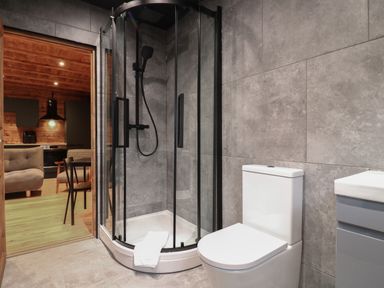 A bathroom with a glass shower enclosure a white toilet and a sink with cabinet at Badger's Burrow in South Luffenham near Edith Weston
