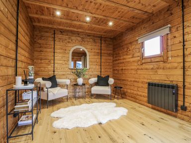 A cozy sitting area with wooden walls and a mirror at Badger's Burrow in Edith Weston