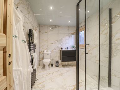 A bathroom with shower, toilet, sink, and towels at Badger's Burrow in Edith Weston