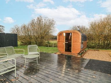 A garden with a wooden sauna and seating area at Badger's Burrow Edith Weston