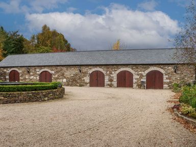 A stone building with five wooden arched doors and a gravel driveway at Ballybeg Pod 6 Ballybeg near Tinahely County Wicklow