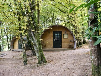Two wooden pods with black doors and chairs outside surrounded by trees at Ballybeg Pod 6 Ballybeg near Tinahely County Wicklow