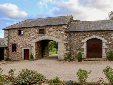 A stone building with arched doorways and small windows with plants in pots at Ballybeg Pod 7 Ballybeg near Tinahely County Wicklow