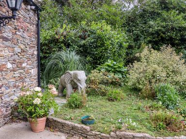 A garden area with a stone elephant statue surrounded by plants and flowers next to a stone wall at Ballybeg Pod 7 Ballybeg near Tinahely County Wicklow