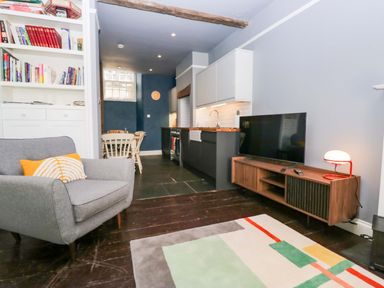 A living room with an armchair and bookshelf at Unicorn Cottage