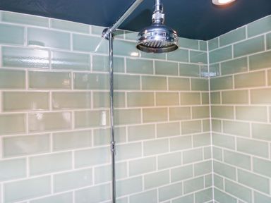 A shower area with green wall tiles at Unicorn Cottage