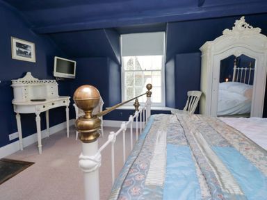 A bedroom with a bed, desk, and mirror at Unicorn Cottage