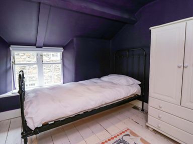 A bedroom with a bed and a wardrobe at Unicorn Cottage