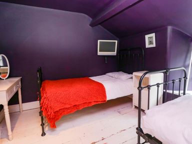 A bedroom with two beds and a dresser at Unicorn Cottage