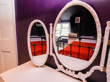 A mirror with a bed and window in view at Unicorn Cottage