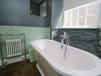 A bathroom with a bathtub and radiator at Unicorn Cottage