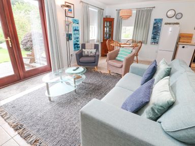 A living room with sofa armchairs glass coffee table and dining table at Chy Lowena in Goldenbank near Budock Water