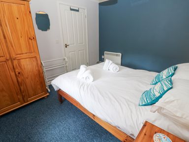 A bedroom with a double bed folded towels wooden wardrobe and a mirror at Chy Lowena Goldenbank near Budock Water
