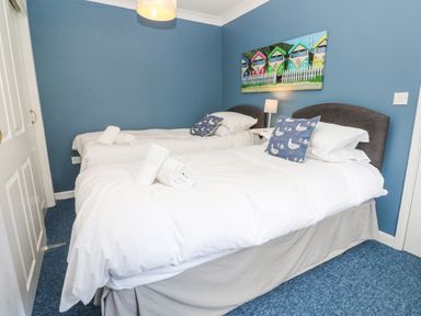 A bedroom with two single beds bedside table with lamp and wall art at Chy Lowena in Goldenbank near Budock Water
