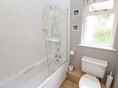 A bathroom with a bathtub shower combination toilet window and tiled floor at Chy Lowena in Goldenbank near Budock Water