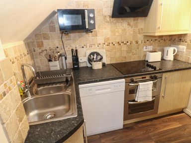 A kitchen with a sink a microwave a dishwasher a stove an oven a toaster a kettle and utensils at 5 Lyonesse Apartments in St Ives