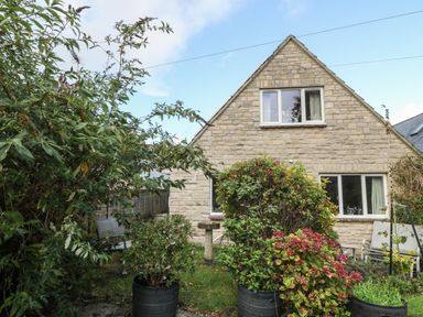 A front garden with potted plants and shrubs in front of a stone house at Old Harry Cottage 16 in Swanage