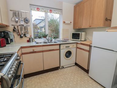 A kitchen with a gas stove sink washing machine microwave and refrigerator at Old Harry Cottage 16 in Swanage
