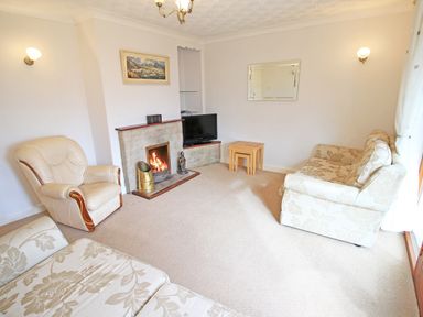 A living room with a sofa armchair fireplace television and nested tables at Artists Cottage in Minffordd near Penrhyndeudraeth