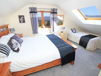 A bedroom with a double bed and a single bed under a skylight at Artists Cottage in Minffordd near Penrhyndeudraeth