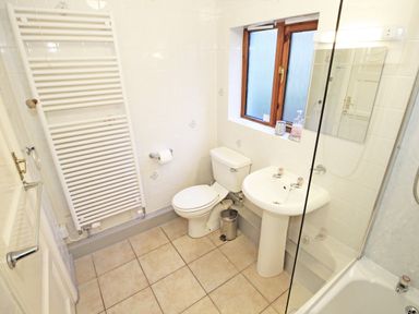 A bathroom with a toilet sink bathtub towel radiator and a window at Artists Cottage in Minffordd near Penrhyndeudraeth