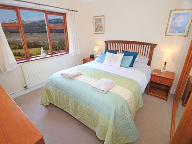 A bedroom with a double bed nightstands lamps and a window with a view at Artists Cottage in Minffordd near Penrhyndeudraeth