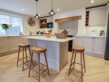 A kitchen with an island and three wooden stools at Beudy Pwll Pridd in Llangollen