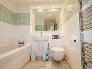 A bathroom with a bathtub sink toilet and a mirror at 6 Willows Green in Aldeburgh