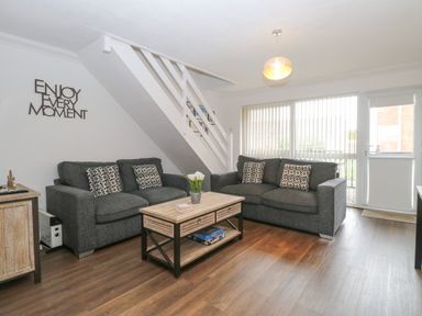 A living room with two sofas and a coffee table under stairs at 102 Waterside Park in Corton
