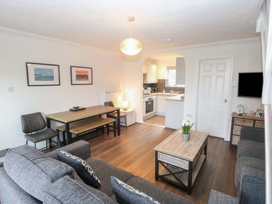 A living room with sofa coffee table dining table and an open kitchen at 102 Waterside Park in Corton