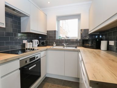 A kitchen with white cabinets black backsplash wooden countertops and appliances at 102 Waterside Park in Corton