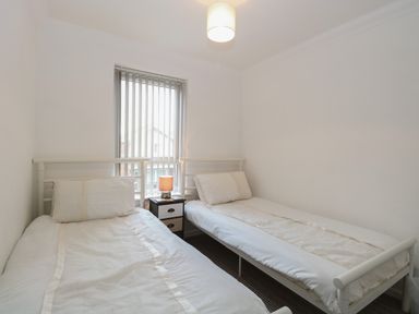 A bedroom with two single beds separated by a small bedside table with a lamp at 102 Waterside Park in Corton