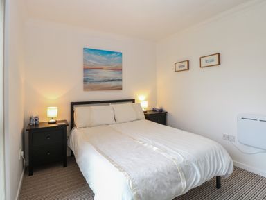 A bedroom with a double bed flanked by two black nightstands each with a lamp and tissue box at 102 Waterside Park in Corton
