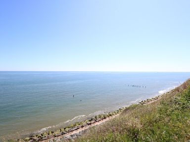 A view of a calm sea with a rocky shoreline and grassy embankment at 102 Waterside Park in Corton