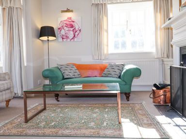 A living room with a green sofa two pillows a glass coffee table rug and a painting at Holm Oak Lodge in Tendring near Weeley