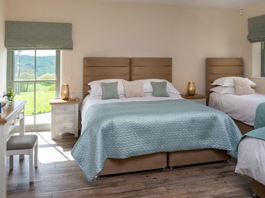 A bedroom with a double bed and a single bed with blue blankets and bedside tables with lamps at High View Barn in Sedbergh