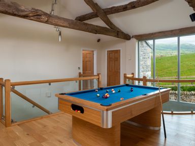 A room with a pool table by large windows and wooden beams at High View Barn in Sedbergh