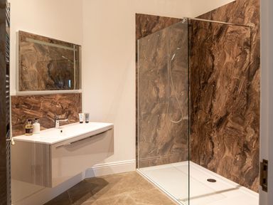 A bathroom with a wall-mounted sink vanity and a walk-in shower with glass partition at High View Barn in Sedbergh