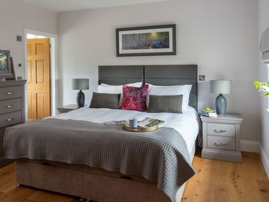 A bedroom with a large bed two bedside tables with lamps a dresser and a framed picture above the headboard at High View Barn in Sedbergh