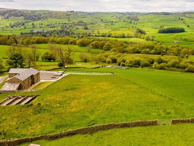 A rural landscape with fields trees and stone barns at High View Barn in Sedbergh