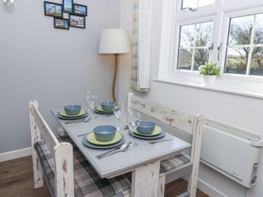 A dining area with a set table for four with blue bowls green plates and wine glasses at The Cwtch in Aberporth