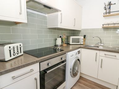 A kitchen with a toaster stove oven washing machine microwave sink and countertop at The Cwtch in Aberporth
