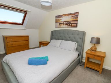 A bedroom with a bed towels on it bedside tables a lamp and a chest of drawers at The Cwtch in Aberporth
