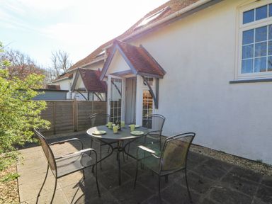 An outdoor patio with a round metal table and four chairs set with plates and cups at The Cwtch in Aberporth