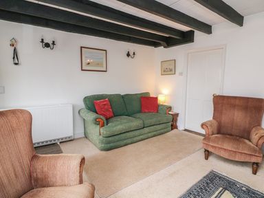 A living room with two armchairs and a sofa with cushions at Vine Cottage in East Prawle