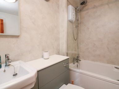 A bathroom with a sink a cabinet a bathtub with a shower at Vine Cottage in East Prawle