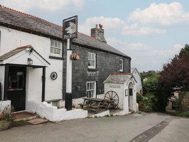 An exterior view of a pub named Pigs Nose with picnic tables outside and a signpost at Vine Cottage in East Prawle